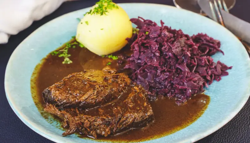 Rinderbraten in dunkler Sauce mit Klößen und Rotkohl. Ein guter Rotwein zum Kochen Rinderbraten macht dieses Gericht perfekt.