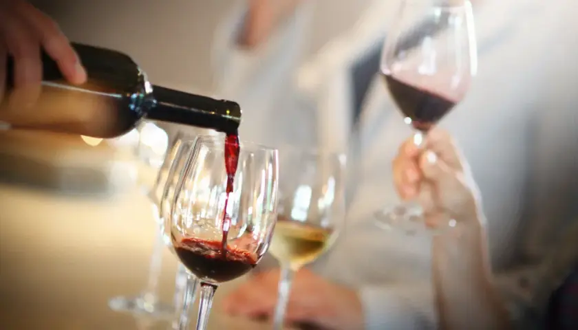 Rotwein wird in ein Glas gegossen, während ein Weinkenner mit einem Fachbegriff die Aromen beschreibt.