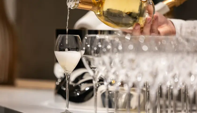 Ein Glas wird mit prickelndem Vranken Pommery gefüllt, daneben stehen weitere Champagnergläser bereit.