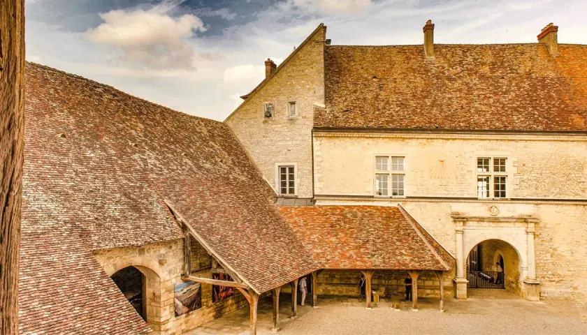 Historisches Gebäude mit Ziegeldächern, ein Torbogen und ein Sonnenuhr. Vielleicht ein Ort, wo man einen exzellenten Chambertin Clos de Bèze genießt.