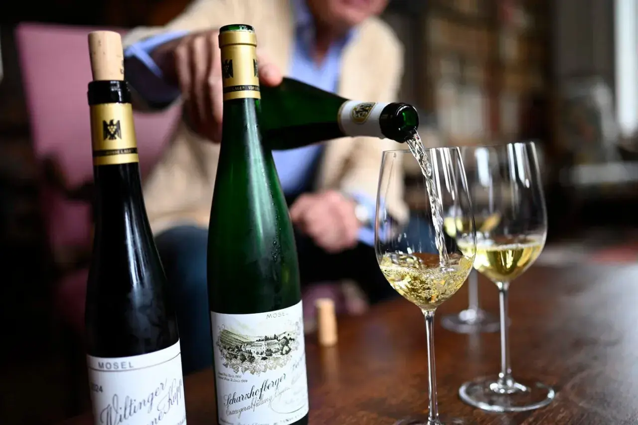 Egon Müller schenkt Wein aus zwei Mosel-Flaschen in Weingläser.