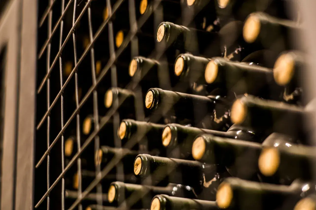 Reihe von dunklen Flaschen mit Korken, die in einem Regal gelagert werden. Vielleicht der teuerste Wein der Welt, der auf seine Reifung wartet.