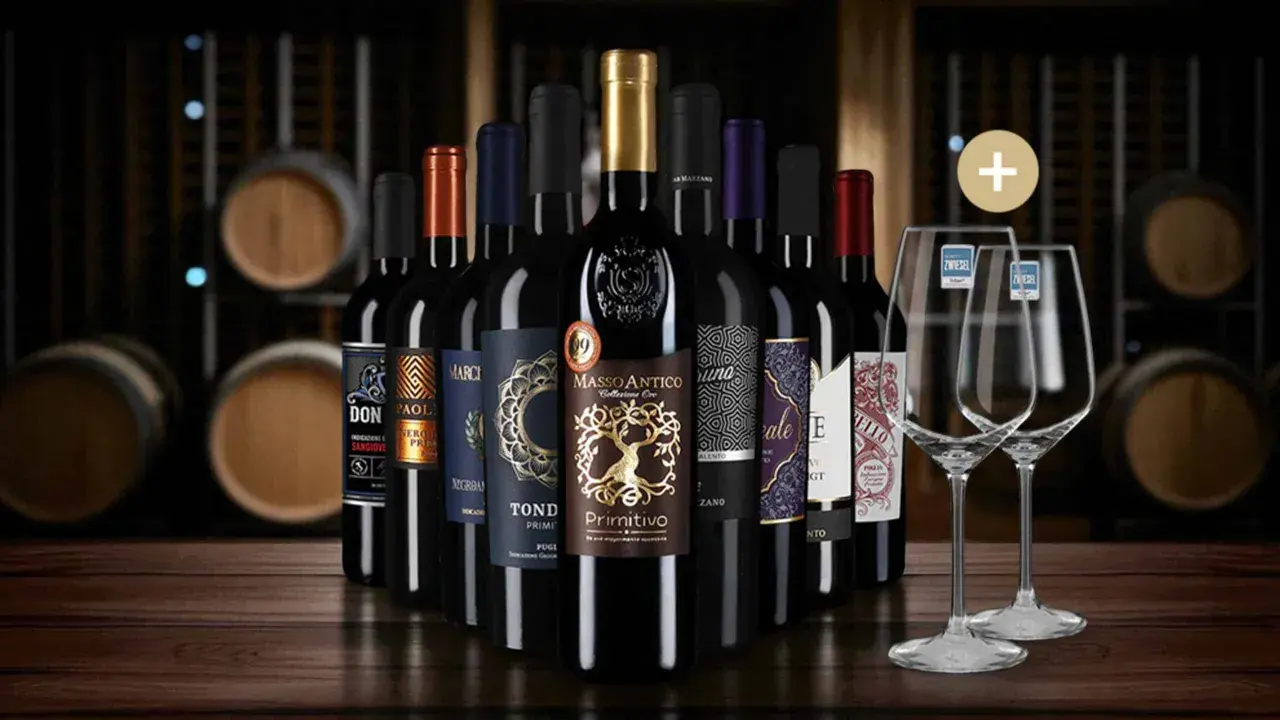 Eine Auswahl an Flaschen Rotwein, die auf einer Holzoberfläche stehen, mit Weinfässern im Hintergrund. Diese Weine könnten Teil einer besten Rotwein Rangliste sein.