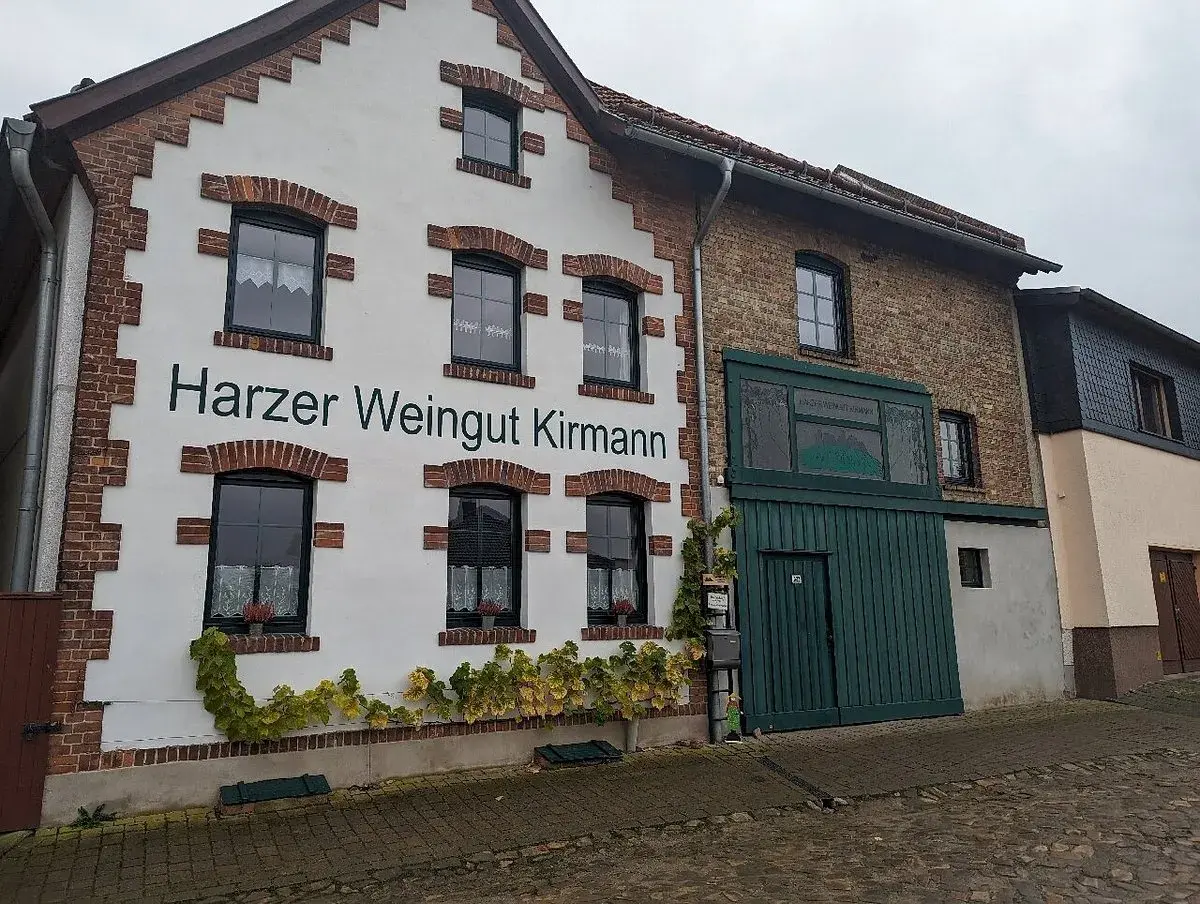 Das Harzer Weingut Kirmann präsentiert sich mit weißer Fassade und roten Ziegelakzenten. Ranken schmücken die Hauswand.