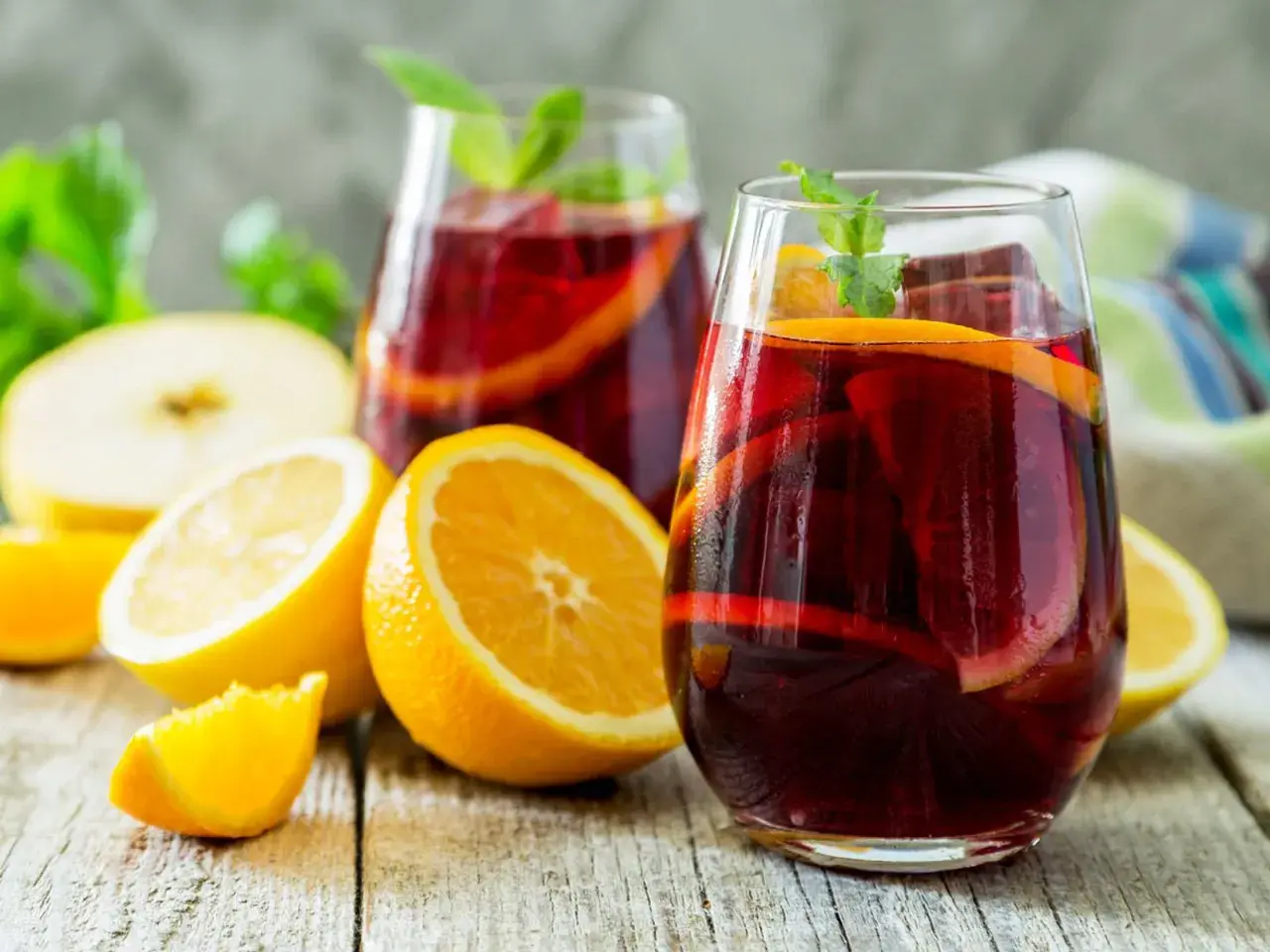 Erfrischender Sangria mit Orangen- und Zitronenscheiben, Minze und Eis. Das beste Sangria Rezept für heiße Tage.