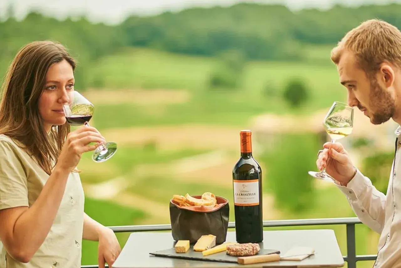 Ein Paar genießt Wein und Käse auf der Terrasse eines Weinguts in Bordeaux. Die Weinprobe verspricht Genuss.