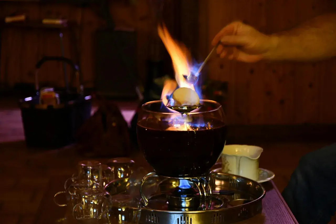Eine alkoholfreie Feuerzangenbowle brennt und verströmt wohlige Wärme. Ein Zuckerhut schmilzt über der Flamme.