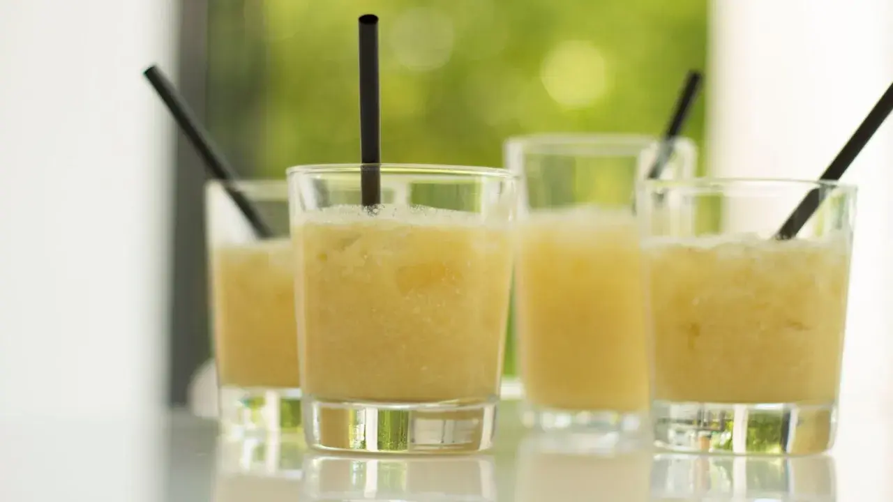 Erfrischende Cocktails, perfekt für ein Coco Vine Rezept. Sonnengelbe Drinks mit Eis und schwarzen Strohhalmen.