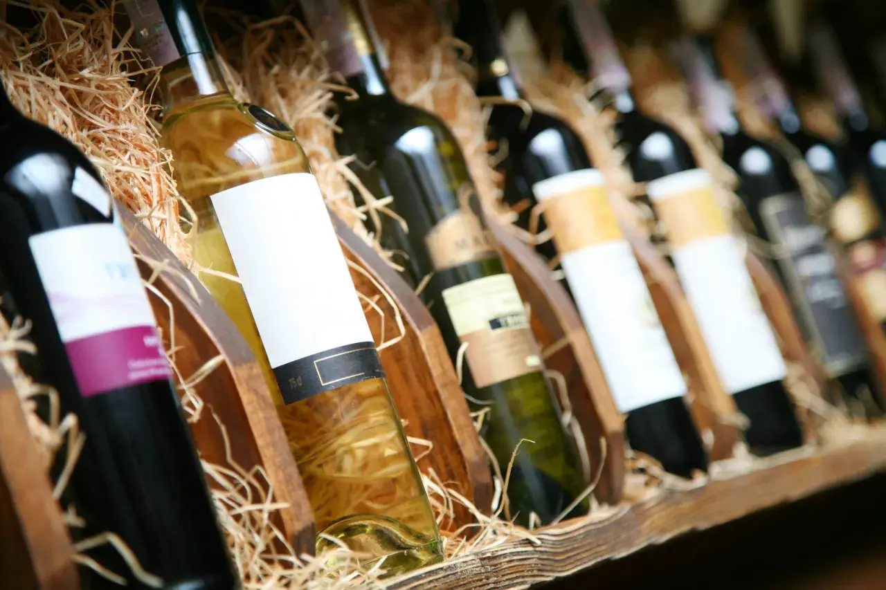 Reihe von Flaschen mit Wein, einige rot, andere weiß, in Holzkisten mit Stroh. Ein Genuss für jeden Weinliebhaber.