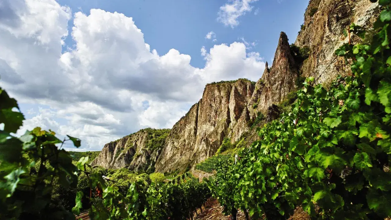 Steile Weinberge am Felsen, die auf die besten Naheweine hoffen lassen. Wolken ziehen über die beeindruckende Landschaft.