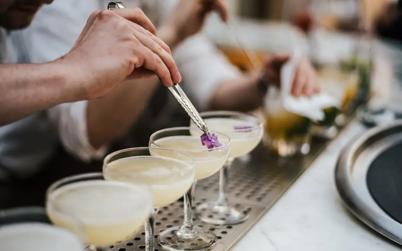Ein Barkeeper garniert einen Cocktail mit Cointreau und Sekt mit einer kleinen Blüte.