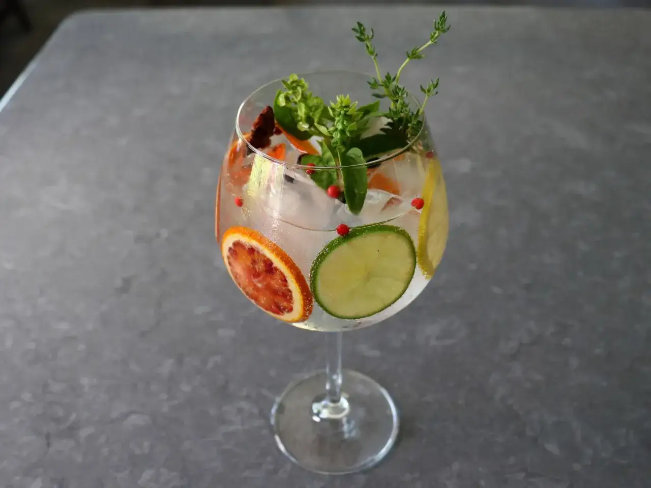 Erfrischender Gin Tonic mit Blutorange, Limette, Kräutern und rosa Pfeffer – einer der besten Gin Cocktails.