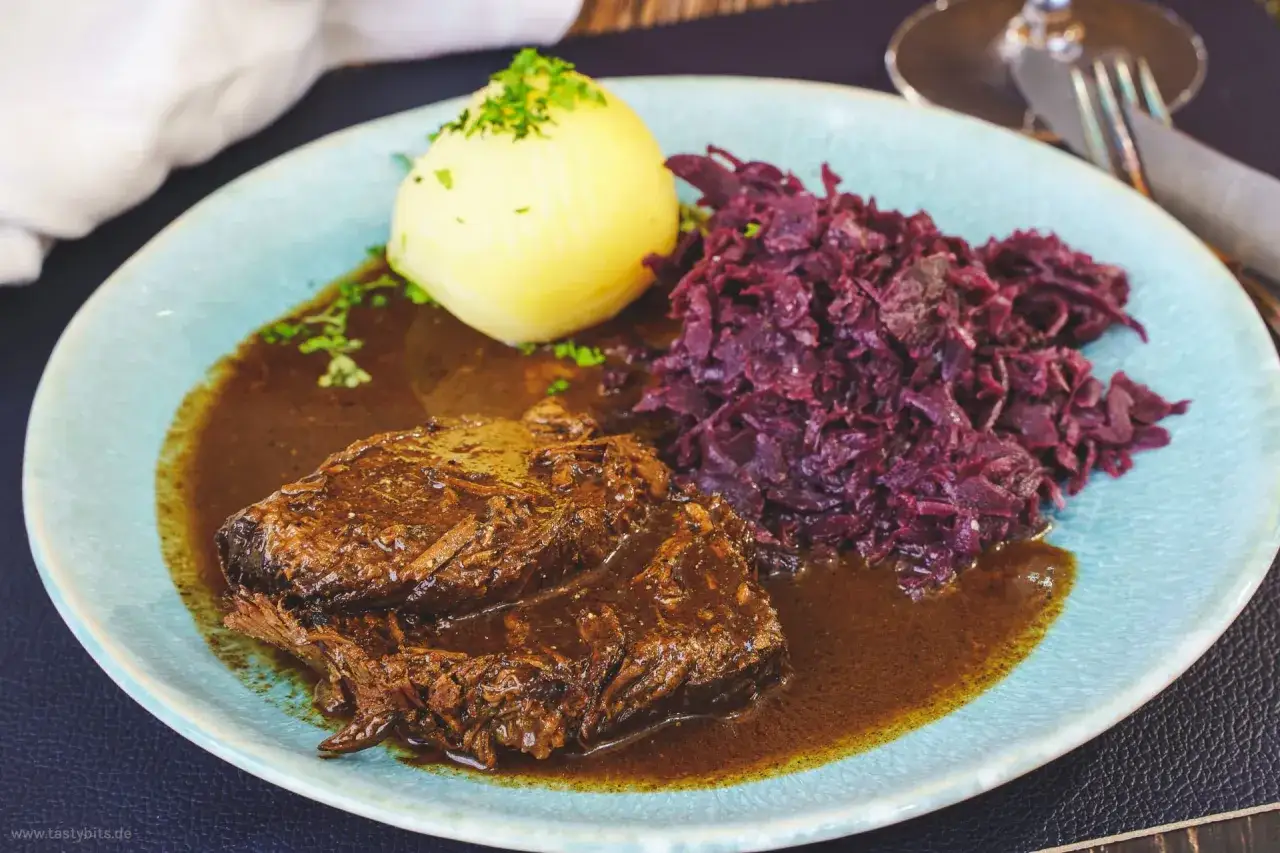 Zarter Rinderbraten in dunkler Sauce, serviert mit Rotkohl und Klößen. Ein Rotwein zum Kochen Rinderbraten wie dieser ist ein Genuss!