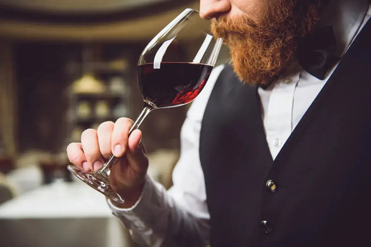 Gerhard Retter, ein Sommelier mit Bart, genie&szlig;t den Duft eines Rotweins in einem eleganten Glas.