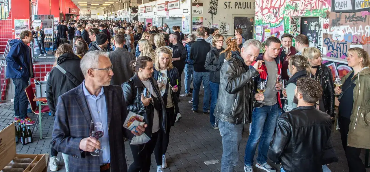 Menschen genießen Wein auf einem Fest. Ein Mann hält ein Glas Rotwein, ein Zeichen für