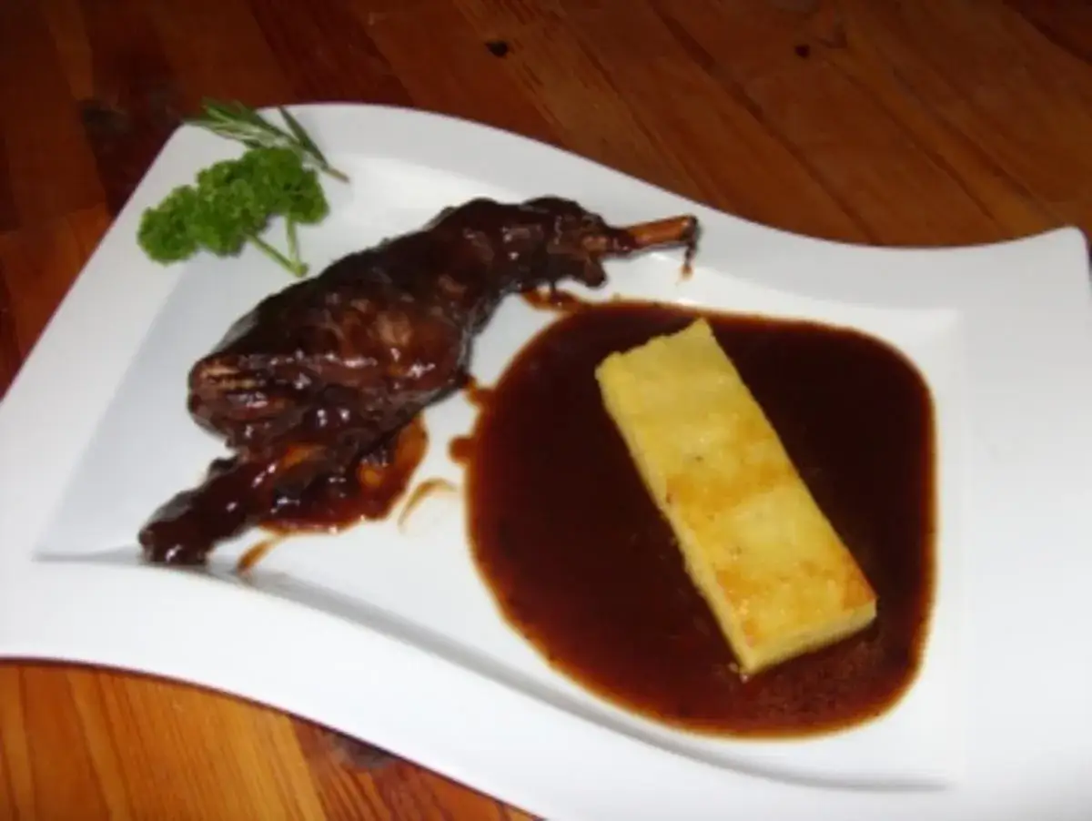 Zart geschmorte Kaninchenkeulen in Rotwein mit Polenta und frischen Kr&auml;utern. Ein Festmahl!