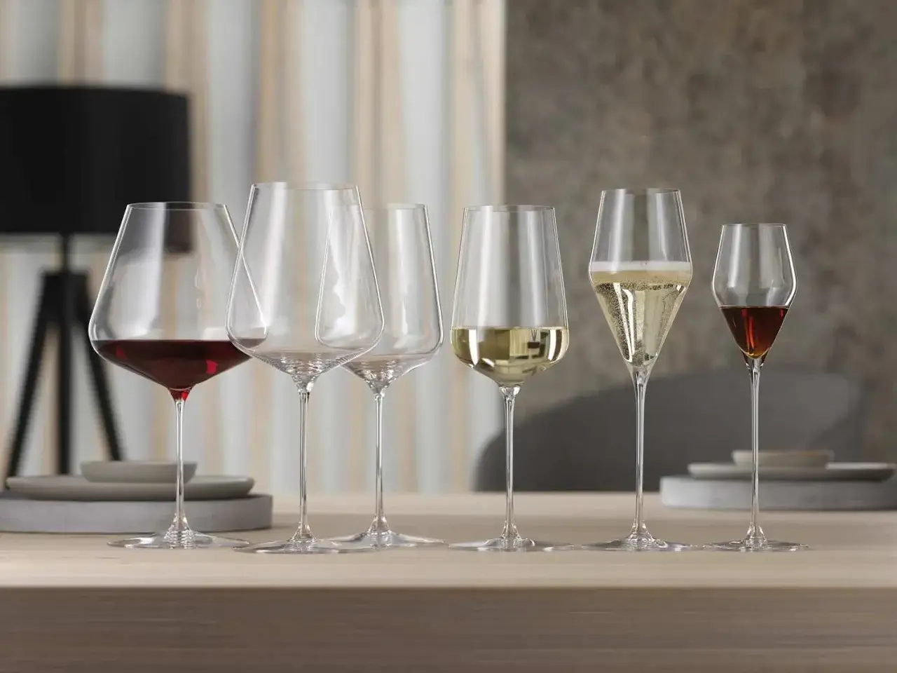 Sechs Weingläser mit verschiedenen Getränken: Rotwein, Weißwein, Sekt und ein dunkler Wein, der an Portwein Sorten erinnert.