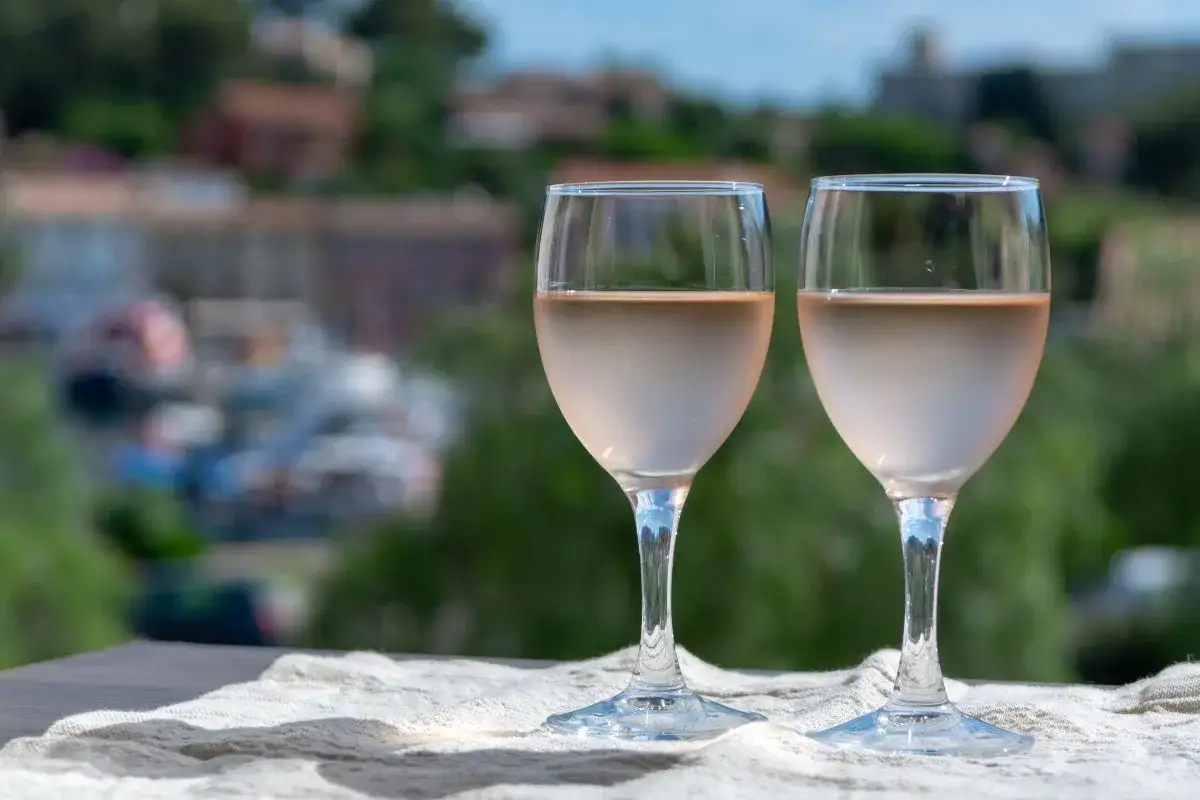 Zwei Gläser Roséwein stehen auf einer Leinentuch vor der Kulisse von maison saint aix.