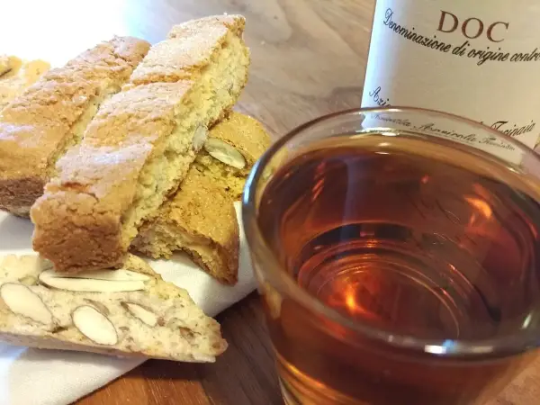 Cantuccini mit Mandeln und ein Glas süßer Dessertwein aus der Toskana, perfekt für einen Genussmoment.