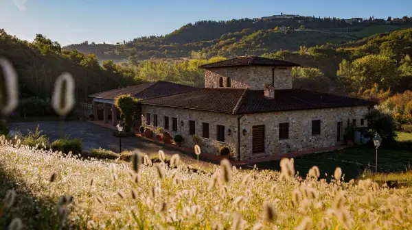 Steinhof mit Ziegeldach im Chianti, umgeben von Hügeln und Gräsern im Morgenlicht.